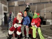 Santa and the Grinch taking pictures with the kids